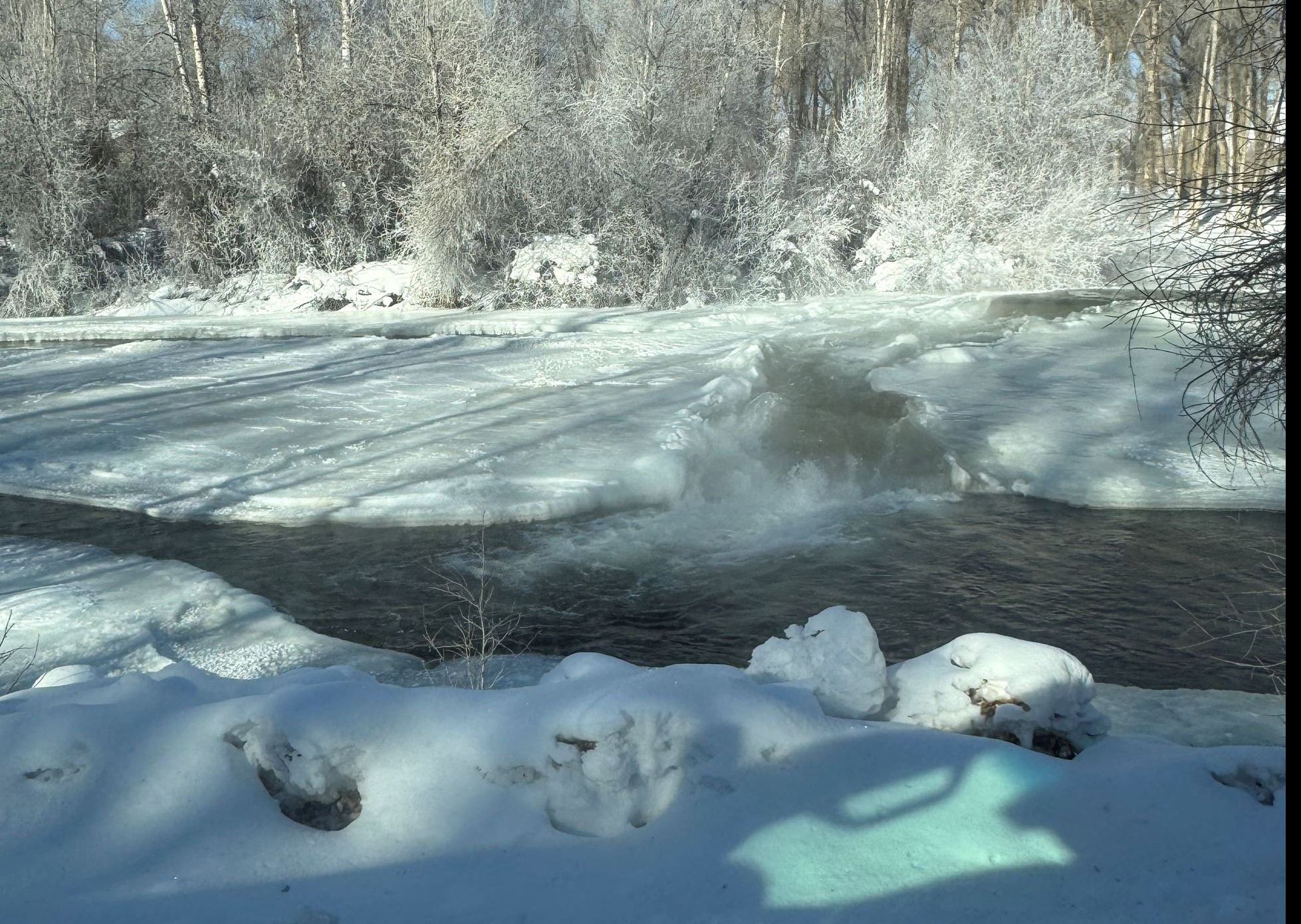 Portion of an ice dam with water flowing over over ice